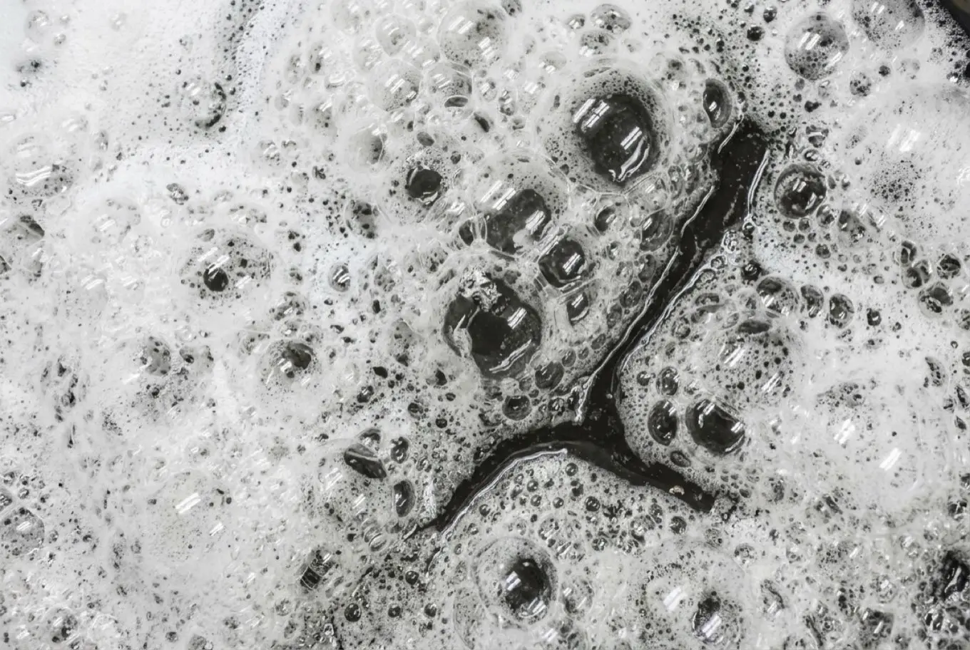 Overhead view of white foam on dark process water.