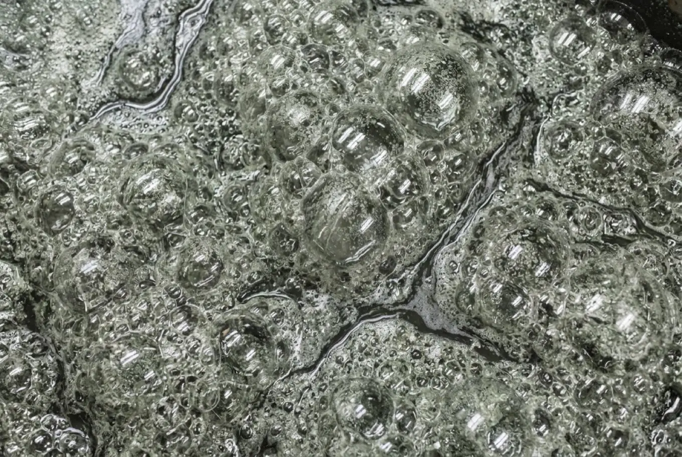 Overhead view of grey-green mineral flotation froth.